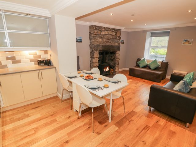 A kitchen and living area with a dining table set for four near a stone fireplace and two sofas at Annest Bethesda