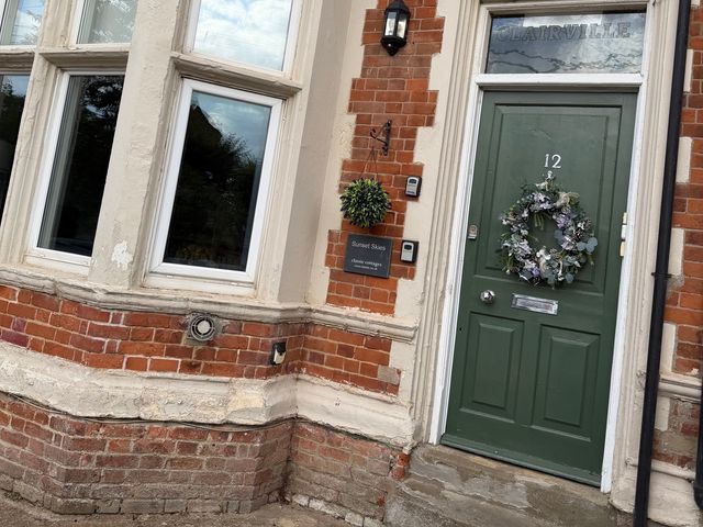 An exterior view of a house entrance with a green door and windows at Clairville, Hunstanton