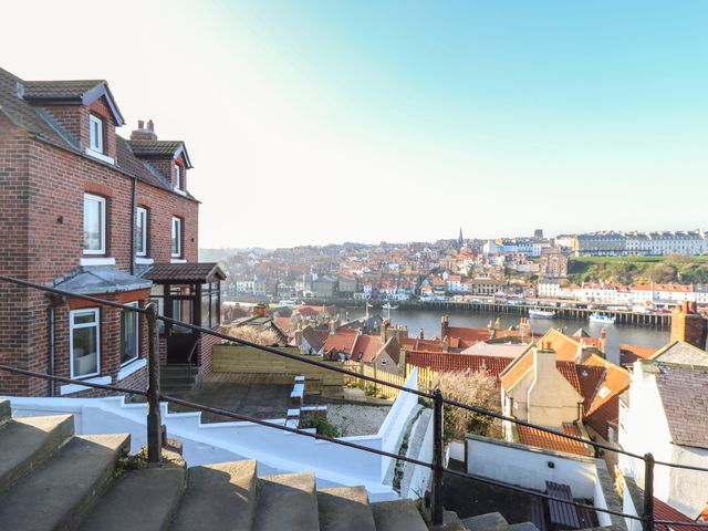 A view of a hillside with steps and railings overlooking a river and town with red roofs at Mariners Watch in Whitby