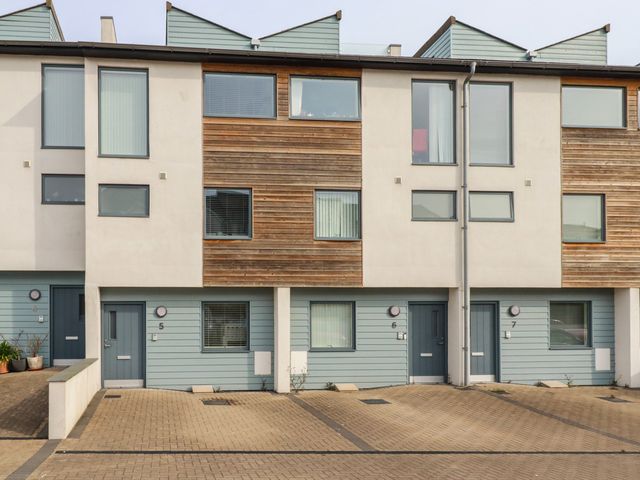 A row of modern townhouses with blue doors and parking spaces at 5 Quay Court in Newquay