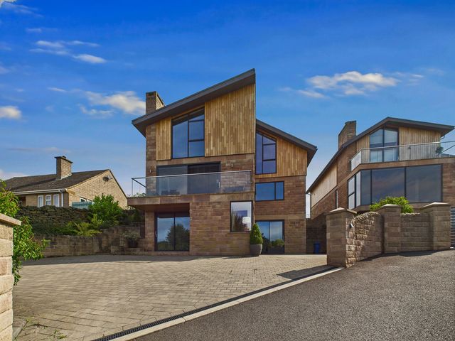 A modern house with a balcony and stone wall at Oakwood House in Tansley near Matlock