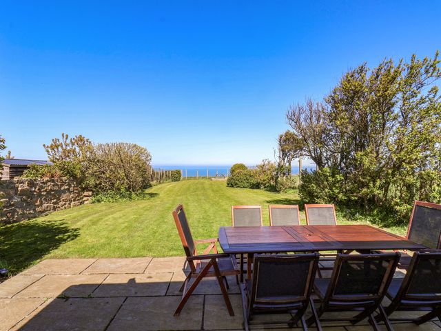 A garden with a table and chairs overlooking the sea at Voebroch in Lythe