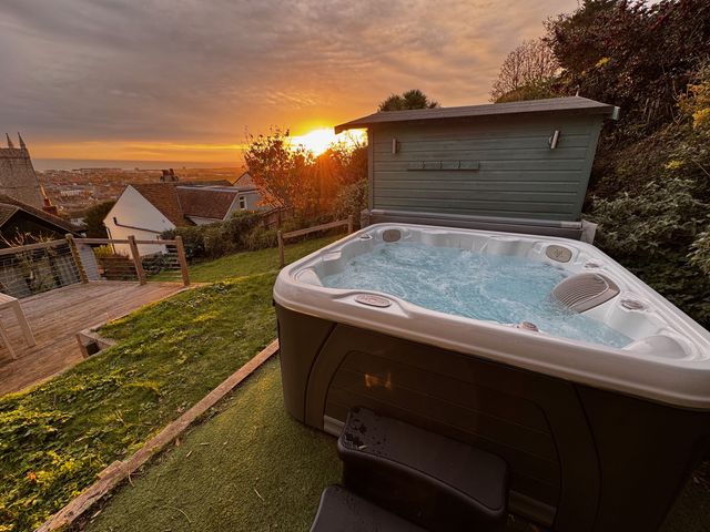 A hot tub in a garden with a sunset at Overchurch in Hythe