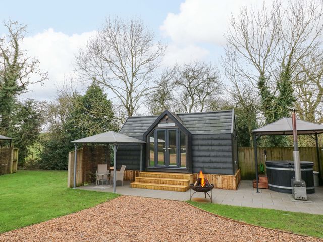 A cabin with a firepit and hot tub at Willow Lodge At Bridge Lake Farm & Fishery Chacombe