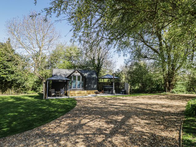 A cabin with a deck and seating area at Willow Lodge At Bridge Lake Farm & Fishery Chacombe