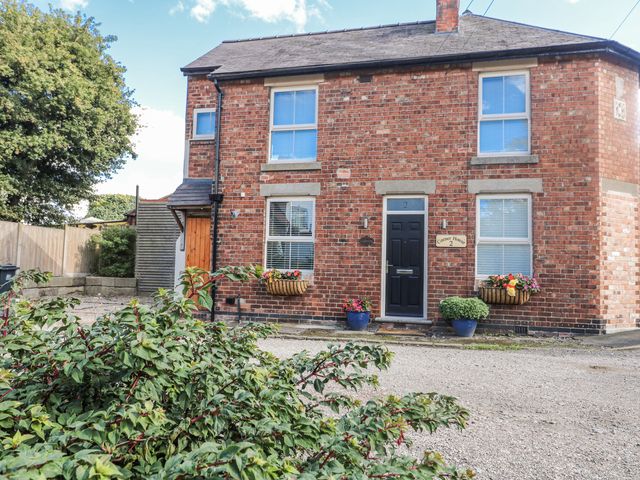 A brick house with flower pots outside at Corner House Cottage in Mapperley Village