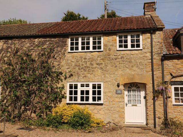 An outdoor view of a cottage with a stone wall and garden at Jasmine Cottage in South Perrott near Mosterton