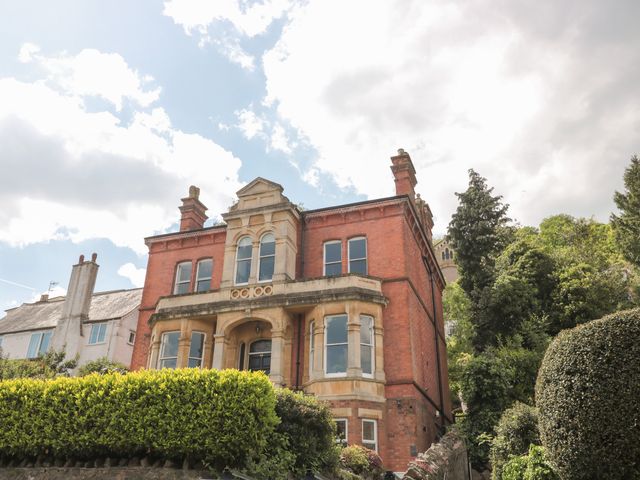A large brick house with arched windows and a front garden with shrubs at The Escape in Malvern