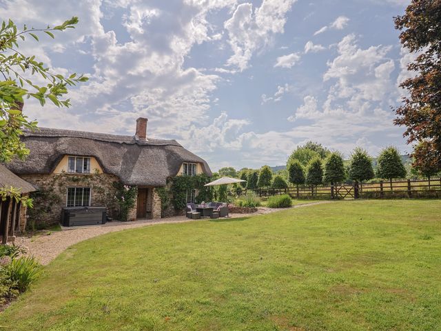 A garden with a thatched house outdoor furniture and trees at Garden View in Wellington