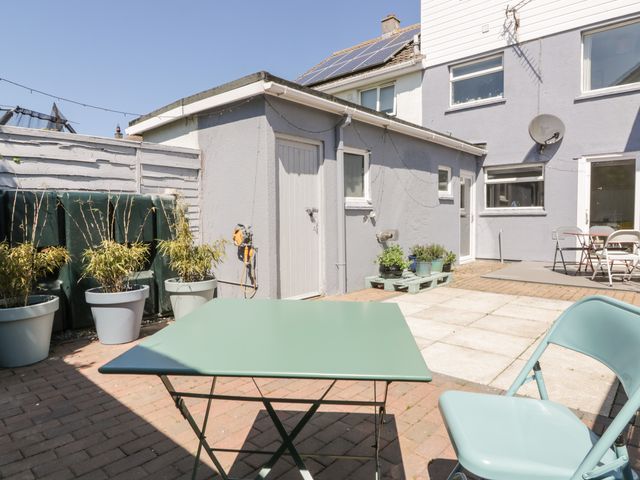 An outdoor patio area with a green table and chair potted plants on a paved floor at Eloen in Crantock