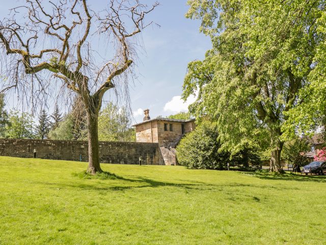 A grassy area with trees and a stone building with steps behind a stone wall at The Coach House - Holmwood in Glasgow