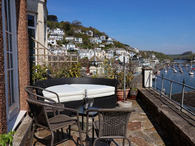 A patio with outdoor seating overlooking a river and hillside houses at Albany in Looe