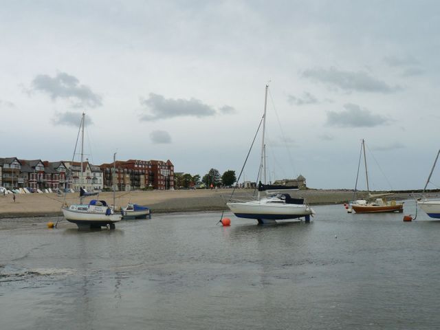 A coastal scene with sailboats anchored near the shore and buildings in the background at Ocean View Apartment in Colwyn Bay