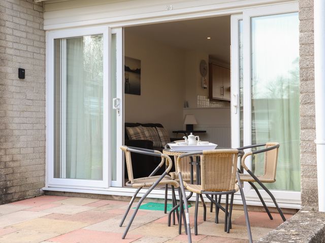 A patio with a table and four chairs in front of sliding glass doors at 24 Atlantic Reach White Cross near St Columb Road