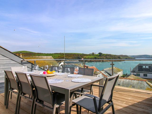 An outdoor dining area with a table and chairs overlooking the water at The Penthouse in Salcombe
