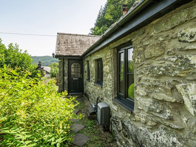An exterior view of a cottage with stone walls and a pathway at Tyn Y Ffynnon in Betws-Y-Coed