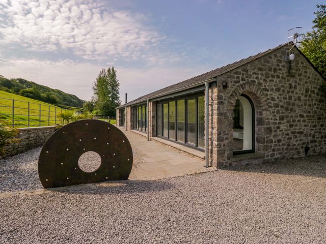 An outdoor area featuring a stone wall and large windows at Limestone in Great Urswick
