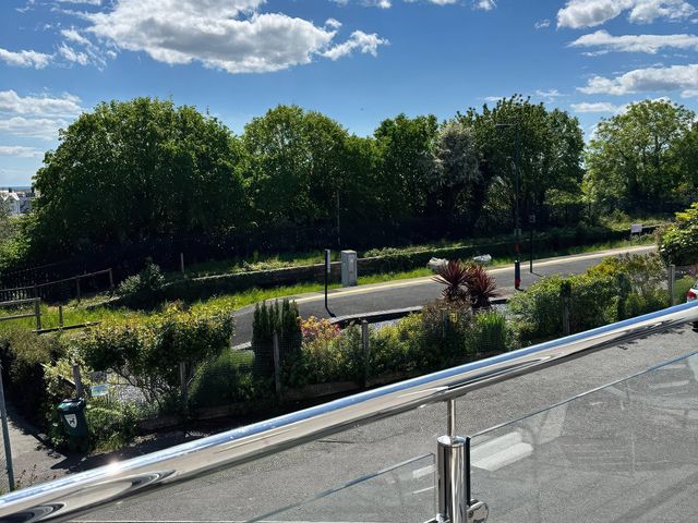 A view of trees and a pathway from a balcony at Ty Copr Perlog Criccieth