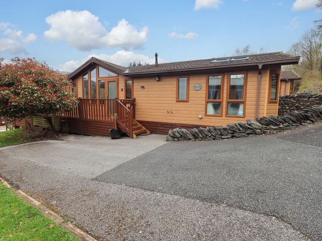 A wooden cabin with a deck and parking area at Elder Lodge Kirkstone 5 Limefitt Park near Windermere