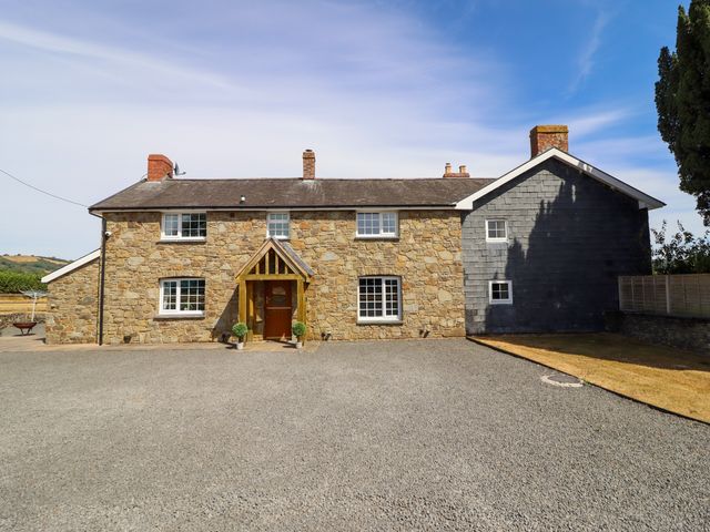 A stone house with a driveway and front entrance at Bodaioch Cottage in Trefeglwys near Caersws