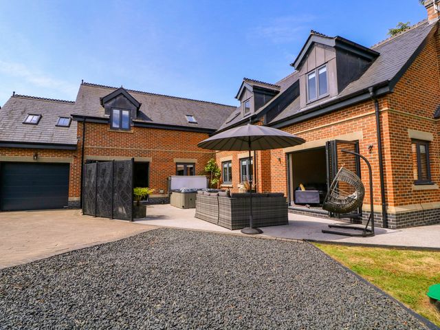An outdoor patio area with seating and an umbrella at Thornbury, Barnard's Green, Malvern