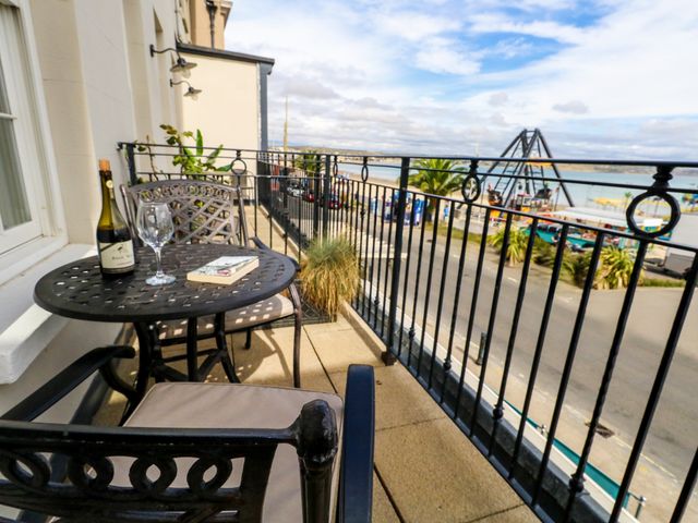 A balcony with a table and chairs overlooking the waterfront at 4 The Beaches Weymouth
