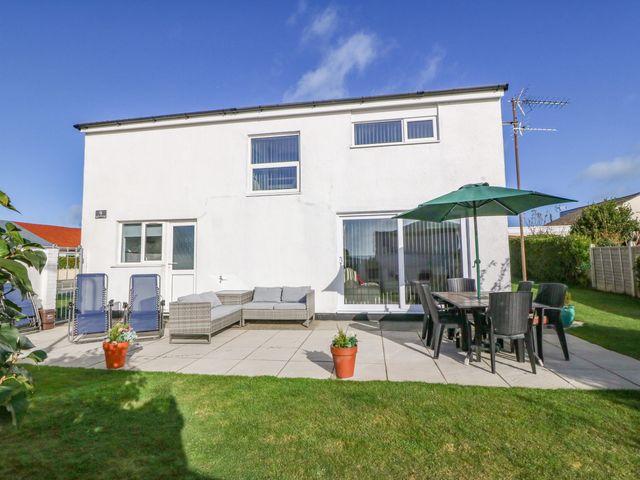 A backyard patio with outdoor seating including a table with umbrella, lounge chairs, and potted plants at Beach Reach in Valley