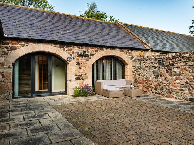 An outdoor seating area with a couch and coffee table at Lupin Cottage in Akeld near Wooler