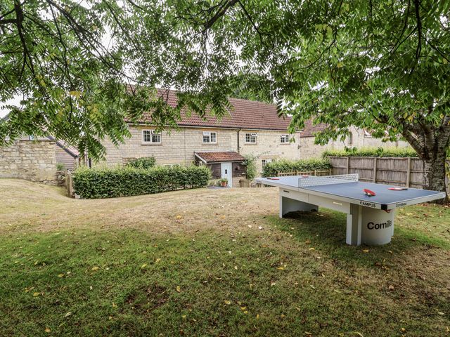 An outdoor area with a ping pong table and a house at The Stable House in Sherborne