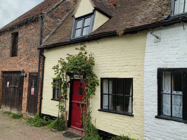 A house facade with a red door and windows in Tewkesbury