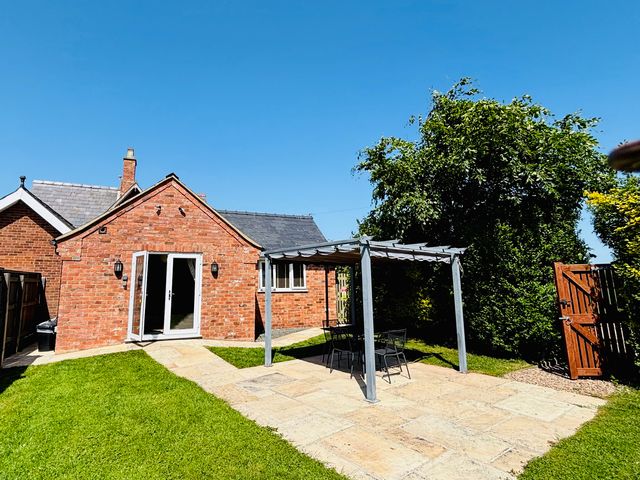 A garden with a brick house and patio furniture at The Old Gate House Annexe in Alford