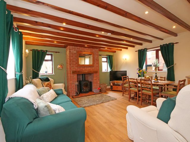 A living room with a sofa, armchair, fireplace, and dining area at Chomley @ Summerfield Farm in Hawsker