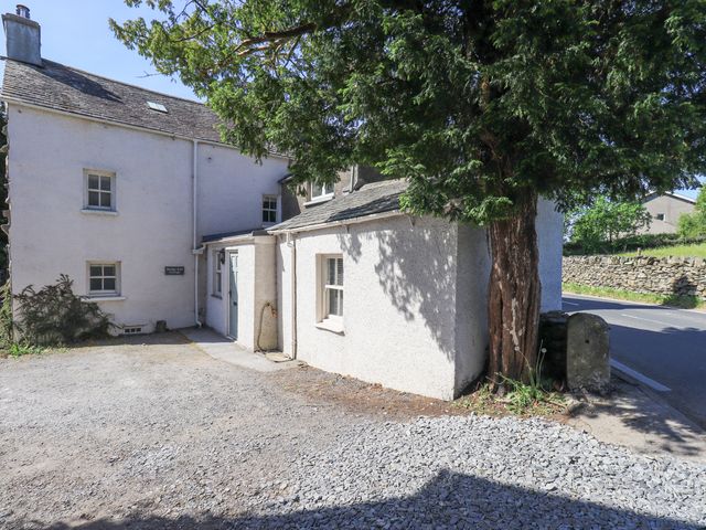 An exterior view of a house with a tree and gravel area at Bridge End Cottage Haverthwaite near Cartmel