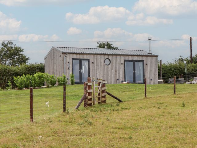 A house with a wooden exterior and a fence at The Pennymoor in Cadeleigh near Tiverton