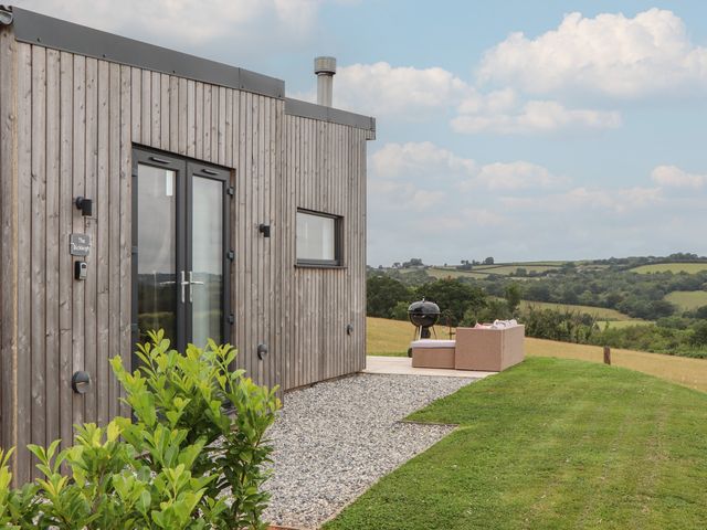 An outdoor area with a wooden cabin and seating at The Bickleigh in Cadeleigh near Tiverton