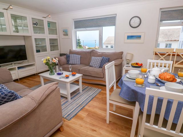 A living room with a sofa and dining table at Atlantic Waves in Carbis Bay