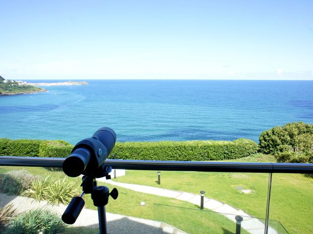 A telescope on a balcony overlooking the ocean with a grassy area and bushes at Elanora in Carbis Bay