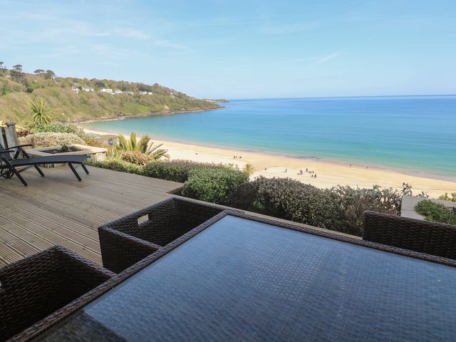 A deck with chairs and a table overlooking the beach at Sapphire in Carbis Bay