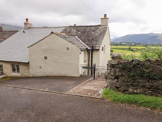 Exterior view of a house with a stone wall and driveway at Squirrel Cottage in Bassenthwaite