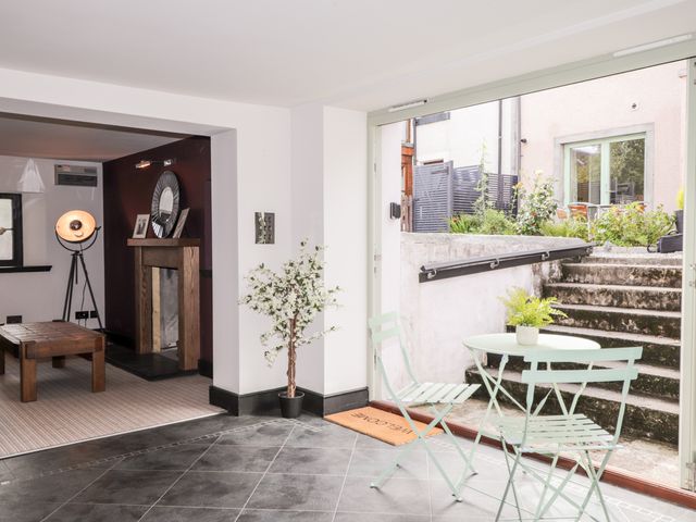 A room with a small table and chairs near an open door leading to outdoor steps and a seating area at Mary Ann Apartment in Inverness