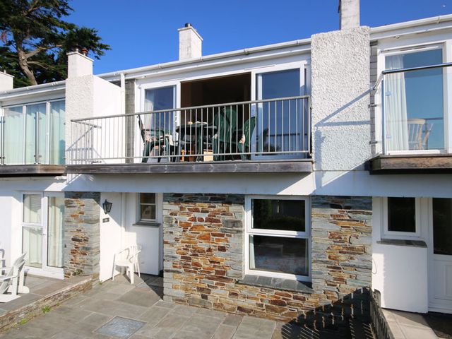 A two-story building with stone and white walls and a balcony with green chairs at Slipway 10 in Rock