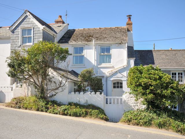 A house with a gate and bush at Coppingers Cottage in Polzeath