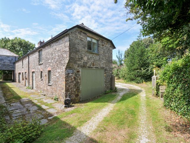 A cottage with stone wall and green door at Orchard Cottage in Polzeath