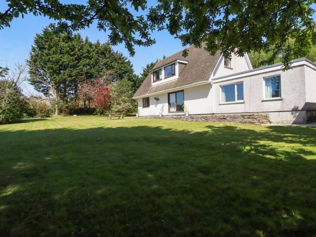 A house with a sloped roof and large grass lawn with trees and a picnic table at Chyrosen in St Day