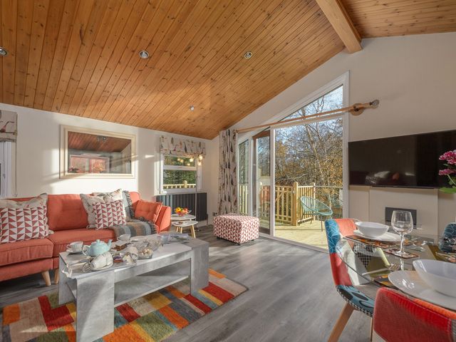 A living room with a sofa table glass dining table and large windows at Oaks One Swarland near Felton