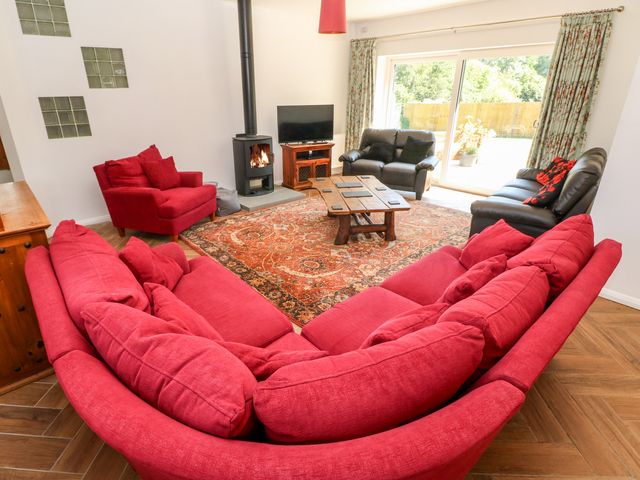 A living room with red and black sofas a wooden coffee table a fireplace and a television at 1 The Warren Robeston Wathen near Narberth