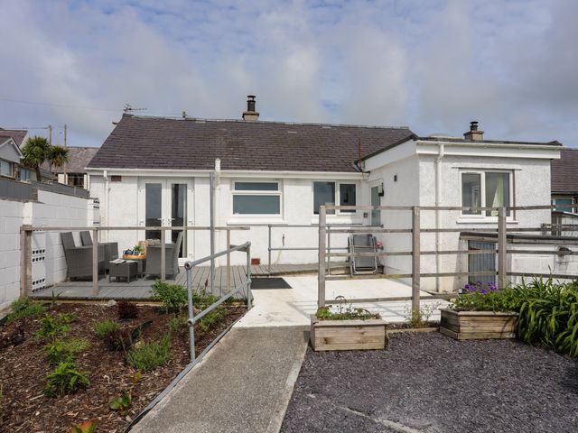 A white house with a patio garden and outdoor seating at 7 Bro Branwen Aberffraw near Rhosneigr