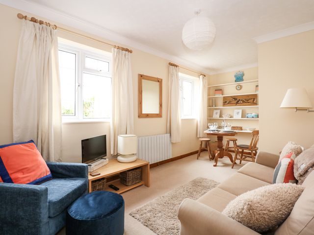 A living room with a beige sofa blue armchair small wooden table and shelves at 16 Norfolk Heights in Docking