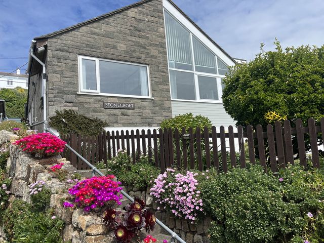 A house with a sign labeled Stonecroft at Praa Sands