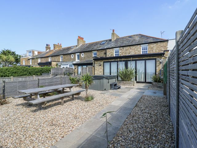 A garden with a dining table and hot tub at Coast Guard House in Swalecliffe